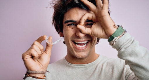 A man smiling and holding an Invisalign aligner, highlighting the excitement of an Invisalign in North Wales, PA dental special.