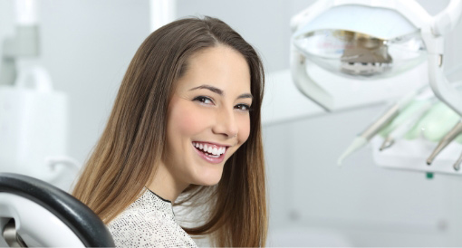 A woman smiling in a dental chair after an iTero scan, teeth cleaning, a whitening kit, and taking advantage of a new patient dental special.